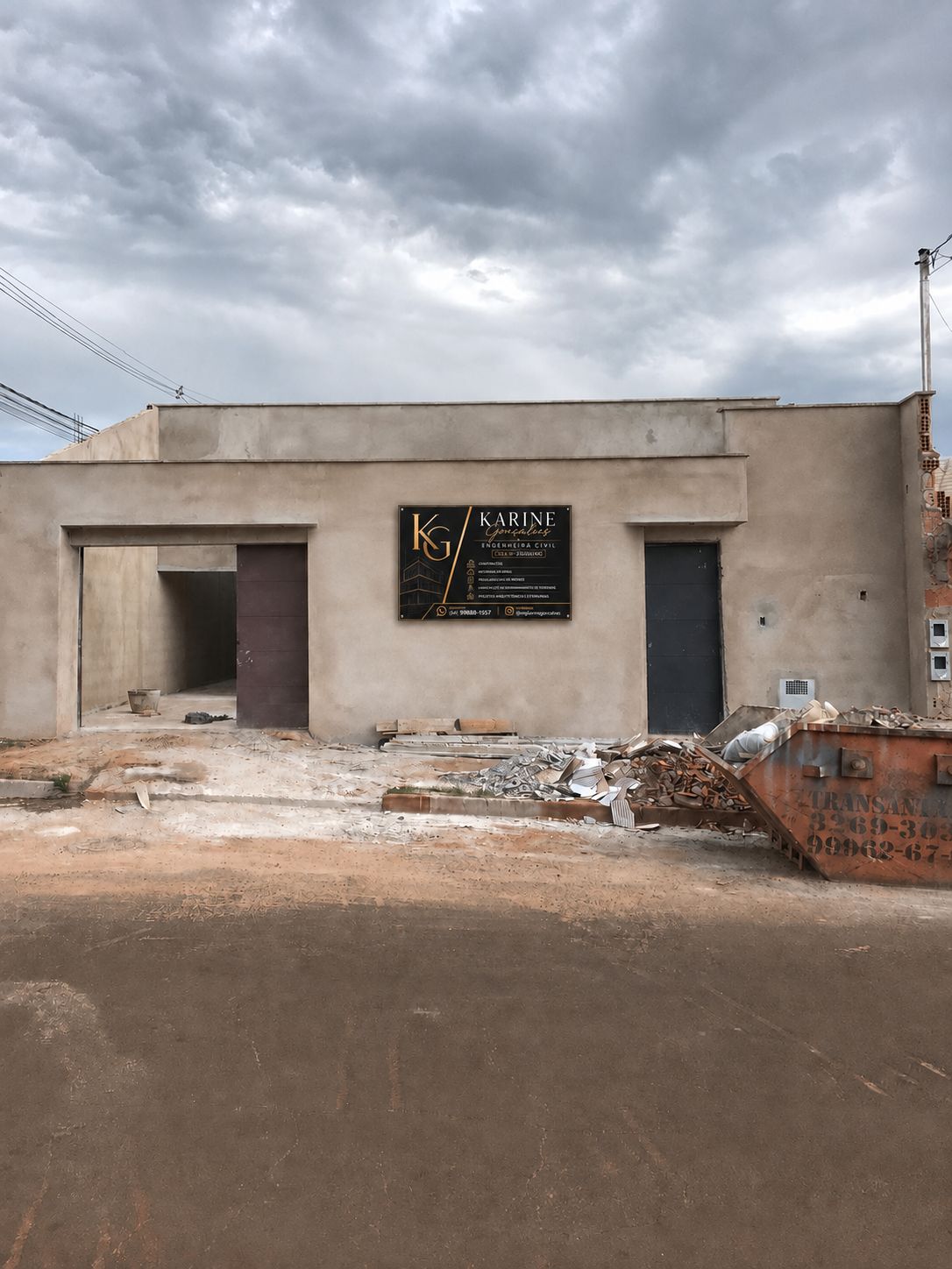Fachada de obra em execução com placa de identificação da engenheira Karine Gonçalves, portas instaladas e caçamba de entulho na frente